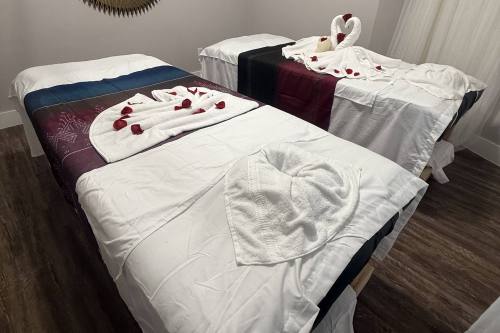 Two massage tables topped with rose petals and towel art.