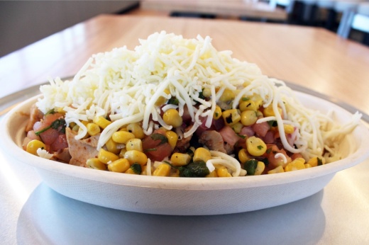 Cardboard bowl filled with chicken, corn, salsa and cheese.