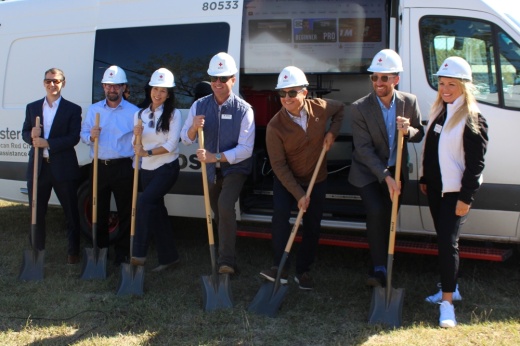 People hold shovels while wearing hard hats