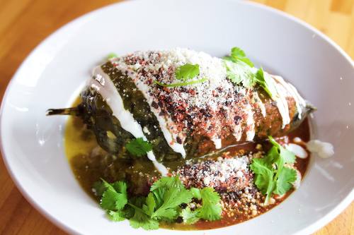 Roasted Chile Relleno from Phoebe’s Diner in Austin, Texas — a poblano pepper stuffed with scrambled eggs and smoked cheddar, topped with ranchero sauce, creme fraiche, cotija cheese, cilantro, and served with red potatoes, a popular gluten-free comfort food and brunch favorite in Austin.