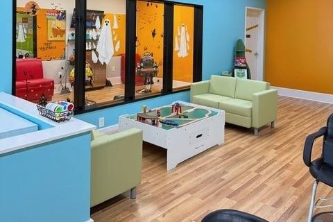 area with couches and a play table in a kids hair salon