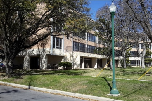 a three story building with many windows behind some trees