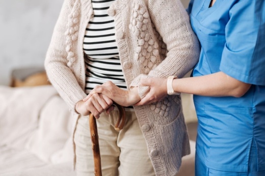 person in blue medical scrubs helping elderly woman