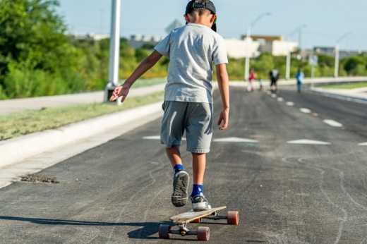A boy is shown skating on a skateboard on the fresh road, which was blocked off to traffic during the grand opening celebration.