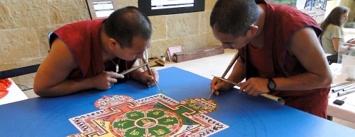 Two Buddhist Tibetan monks work on creating a sand mandala in Austin City Hall on April 15.