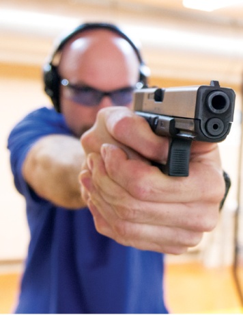 Hood demonstrates proper firearm grip and stance at Shady Oaks Gun Range in Cedar Park.