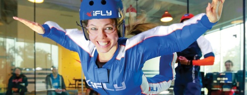 An iFly flight instructor assists a flyer in the wind tunnel. Customers get 60 seconds of flight time.