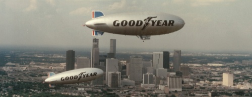 Two versions of the Goodyear blimp cruise above the city of Houston.