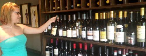 Bartender Hannah Fogle selects a bottle of wine from Crush Wine Loungeu2019s extensive collection.