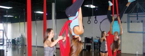 Owner Rachel Tisdale (left) helps lead instructor Megan Reaneau into a silk lyra.