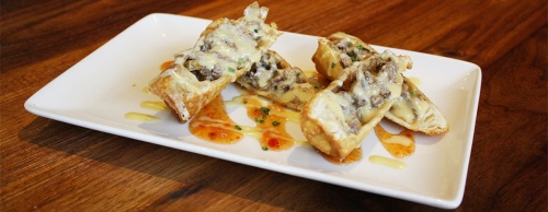 The cheesesteak eggrolls features sweet and spicy chili sauce.