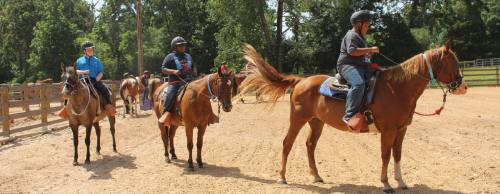 A group of campers ride horses during Kamp Ku2019aana at Camp Cullen in June.