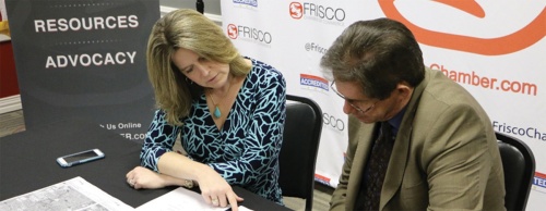 Chamber President Tony Felker (right) reviews an agreement between Frisco and Brazos Electric.