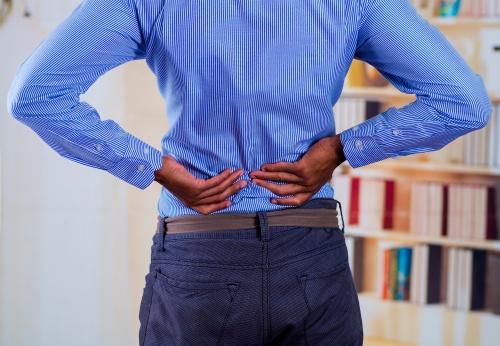 Man touching his back with his two hands, back pain.