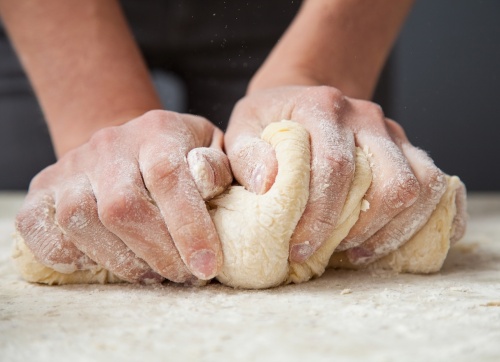 Woman's hands knead dough on a tablen