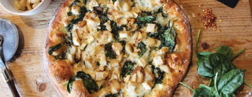 Pizzas include the Flying Garlic, topped with garlic butter, spinach, roasted garlic, grilled chicken breast, feta cheese and crushed red peppers ($9.95-$20.95).