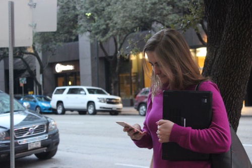 Austin resident Kate Hrdina scans downtown Austin on her phone for available ride-hailing options. Eight companies operate in the city after Uber and Lyft voluntarily left in May.