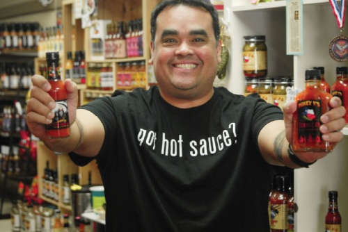 Valencia holds up two of his original sauces, Reaper Unleashed (left) and Texas Exu2019s. Valencia said Reaper Unleashed is his favorite of his own hot sauces.