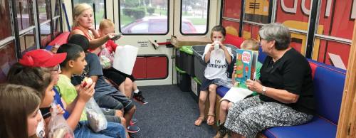 Retired Alvin ISD librarian Elke Crow reads to children in the book bus while they eat their lunch provided by AISD. Students can borrow up to three books per visit.