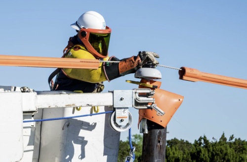 A Pedernales Electric Cooperative worker attends to a power line.