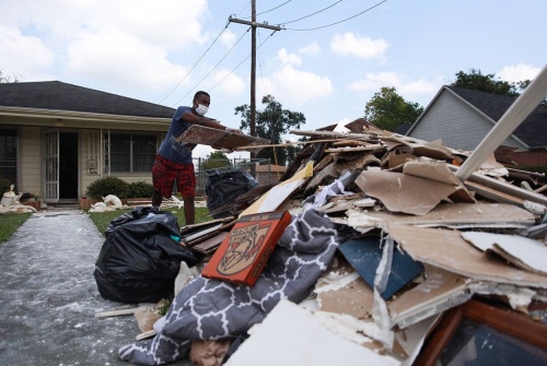 Myles Broussard tosses pieces of drywall into a pile of trash and storm debris outside his home in Beaumont, Texas on Sept. 4, 2017. 