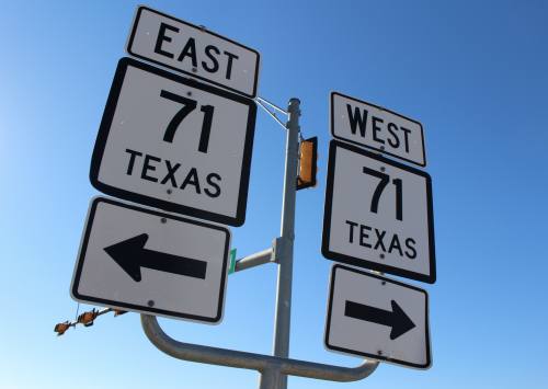 Signs point the way for motorists at the intersection of TX Hwy. 71 and Bee Creek Road.
