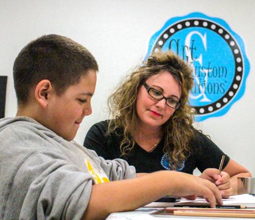 Owner Kelly Kronfield checks on William Bradley Masuno, 12, a student practicing his shading work with color pencils.