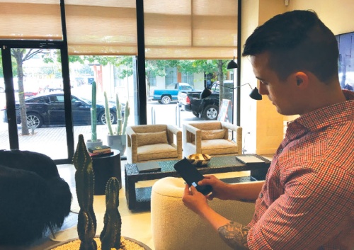  Assistant Design Sales and Sales Representative Kade Sheldon lowers the blinds at the showroom using a smartphone app. 