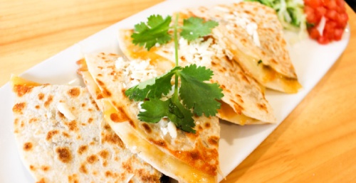 The steak quesadillas dish incorporates a blend of cheddar and Monterey Jack cheese, topped with queso fresco and served with a side of tomatoes, lettuce, sour cream and guacamole. 