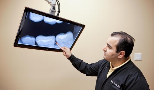 David Panahi, a dentist with Lake Travis Dentistry, looks at a patient's teeth.