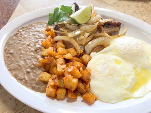 Rancho grande breakfast plate ($9.95) nA pork chop is served with grilled onions, cilantro, eggs, refried beans and potatoes.