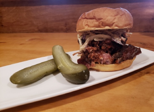 A pulled-pork sandwich comes at Jimmy Vega's Smokehouse in Georgetown comes with homemade pickles.