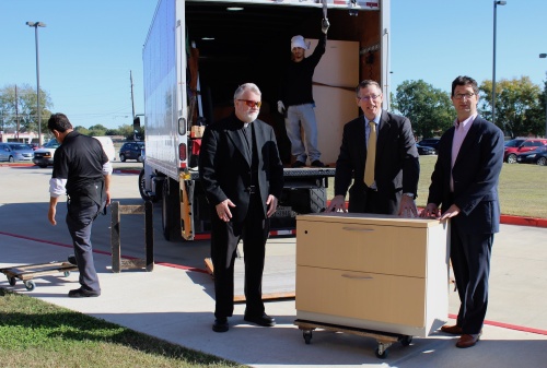 From left: Father Steve Sellers and principal Tim Gallic of St. John XXIII College Preparatory accept furniture donations in November from SABIC, represented by Kevin Wright.