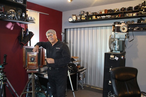 Vic Cherubini, president and founder of Epic Software Group and the Epic Creative Co-op, stands alongside a portion of his camera collection. 