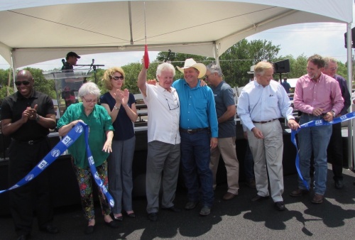 Travis County Commissioner Gerald Daugherty holds scissors up in celebration with Hays County Commissioner Mark Jones at the May 25 ribbon cutting for SH 45 SW. 