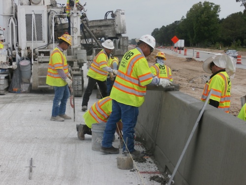 Crews working on Hwy. 290 smooth out freshly-poured concrete on a railing for the widened outbound mainlanes near Mason Road in Cypress.