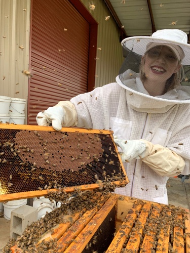 Winding Creek Apiary and Bee Supply employee Jillian Weaver holds a beehive frame.