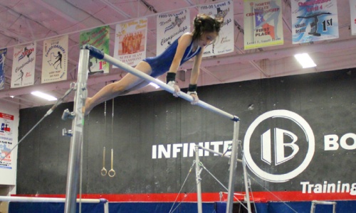 A student practices her technique on the uneven bars. 