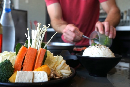 At Yoshi Shabu Shabu, guests select their choice of meats, which is then served with a plate of vegetables, sauces and a pot of broth on a stove in the middle of each table.