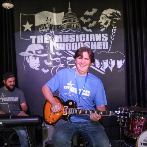 Co-owner Tony Walsh plays a guitar on stage.