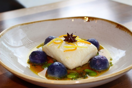 Alaskan halibut is served with fresh fennel, smoked purple potatoes and fava beans in a citrus saffron broth.