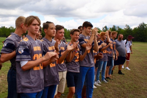 Aristoi Classical Academy football players cheer as the headmaster cuts the ribbon for a new athletic field. n