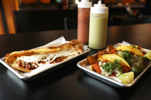 Quesadillas ($9), left, are filled with a choice from 11 meats, lettuce, queso fresco and sour cream. The chicharron, barbacoa and carne asada tacos ($1.75 each), right, are topped with cilantro and onions and served with a side of spicy potatoes and limes.