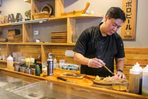 Umami Sushi owner David Lee puts the finishing touches on a seared scallop and yellowtail nigiri behind his sushi bar.