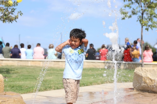 Tyler Nukor, age 3, reacts to one of the spray features of the water stream at the opening of Liberty Playground.
